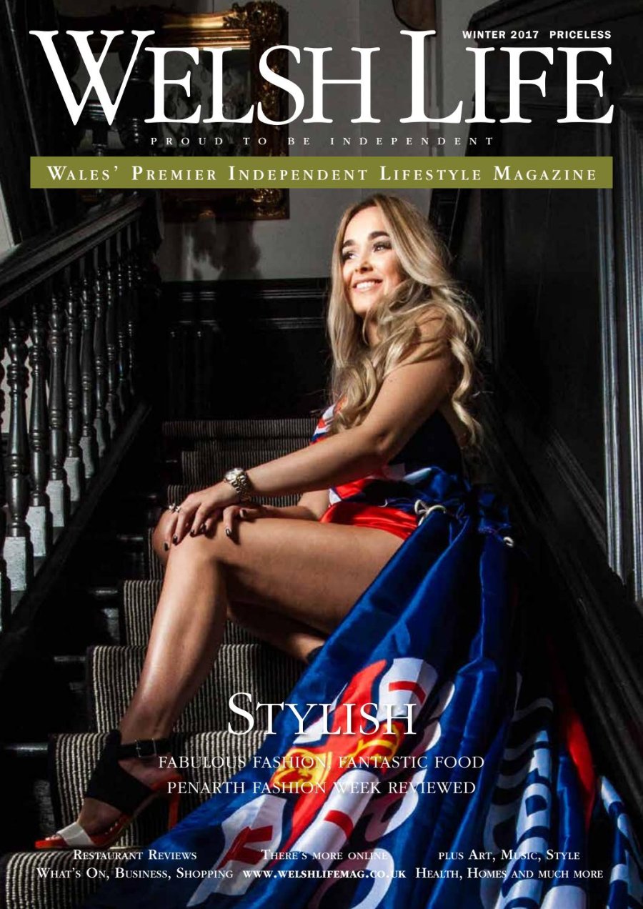 Welsh Life Winter 2017 cover. A smiling young woman with long blonde hair sits on a carpeted staircase in a dark panelled hall, wearing a flowing gown printed in red, white and blue that spills down the stairs, with black heels and a gold watch. Headline: Stylish.